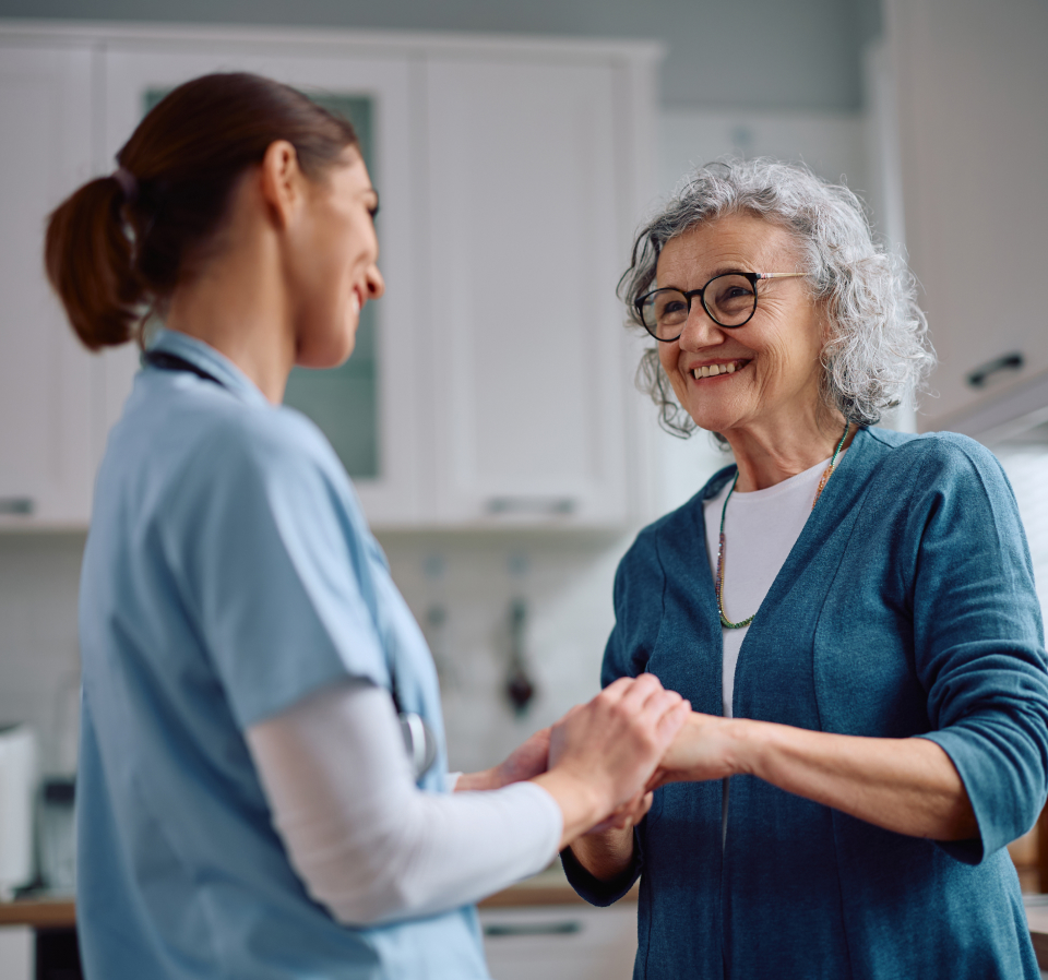 Clinician holding an older patient's hands during a home visit